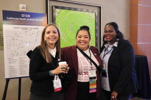 Three woman smiling at a conference